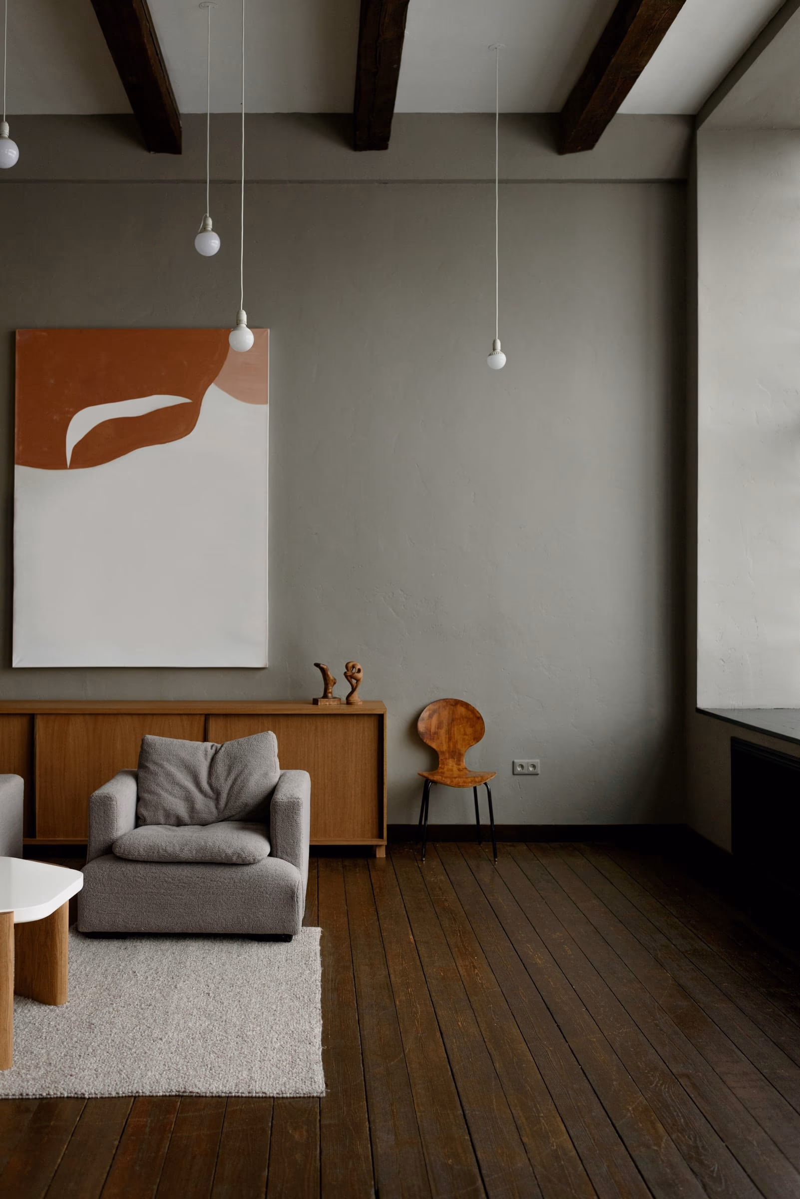 Living room with a low teak credenza, boucle seating and bare pendant lamps against lime-washed walls