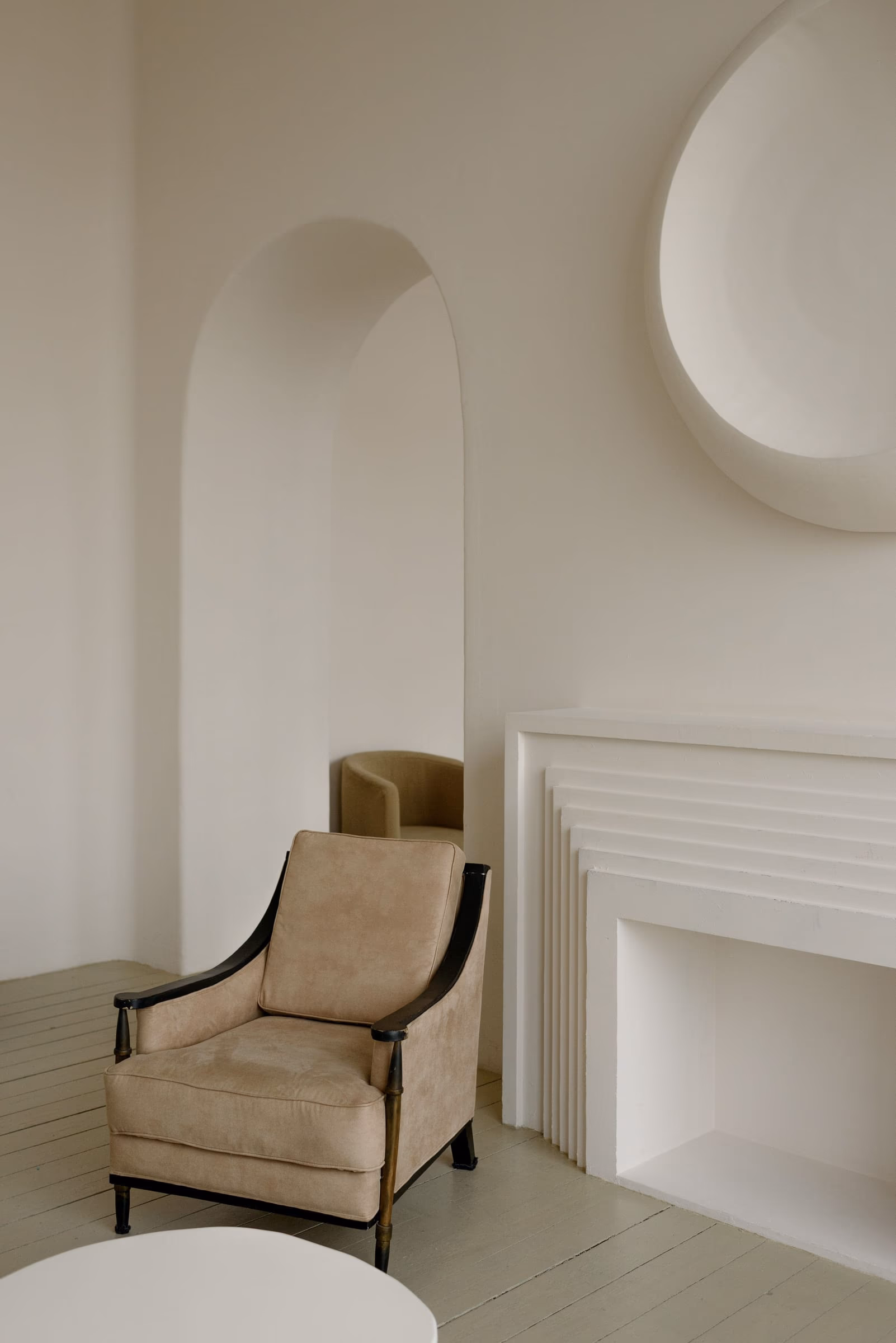 Arched plaster niches in graded whites, with a single upholstered chair below