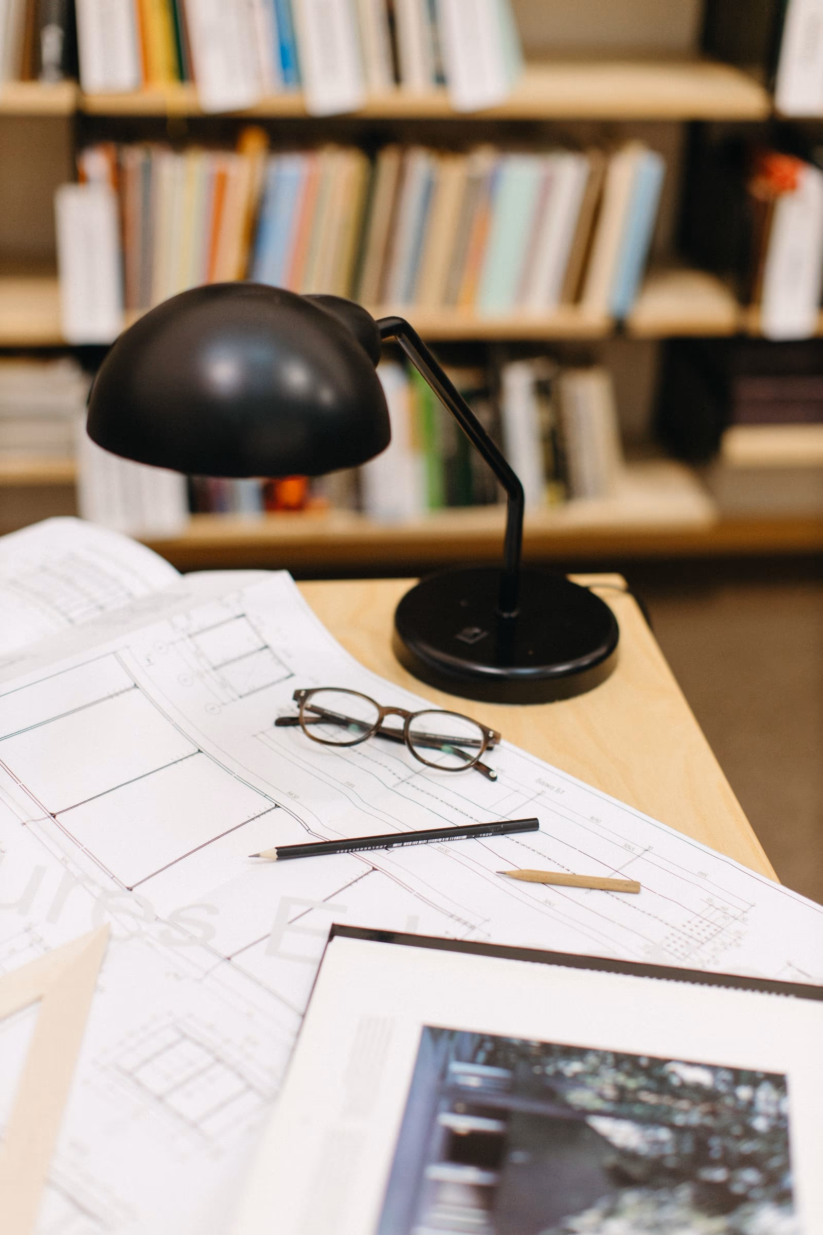The principal's desk, with a set of working drawings open beneath the task lamp